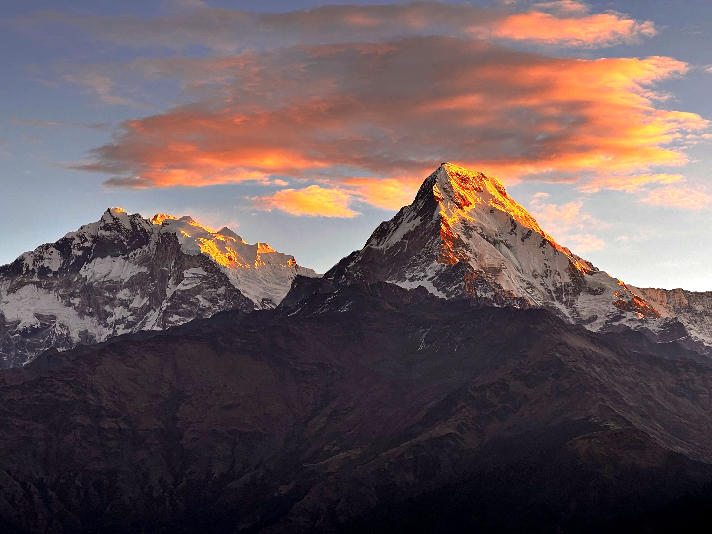Annapurna South and Hiunchuli lit at sunset under orange clouds
